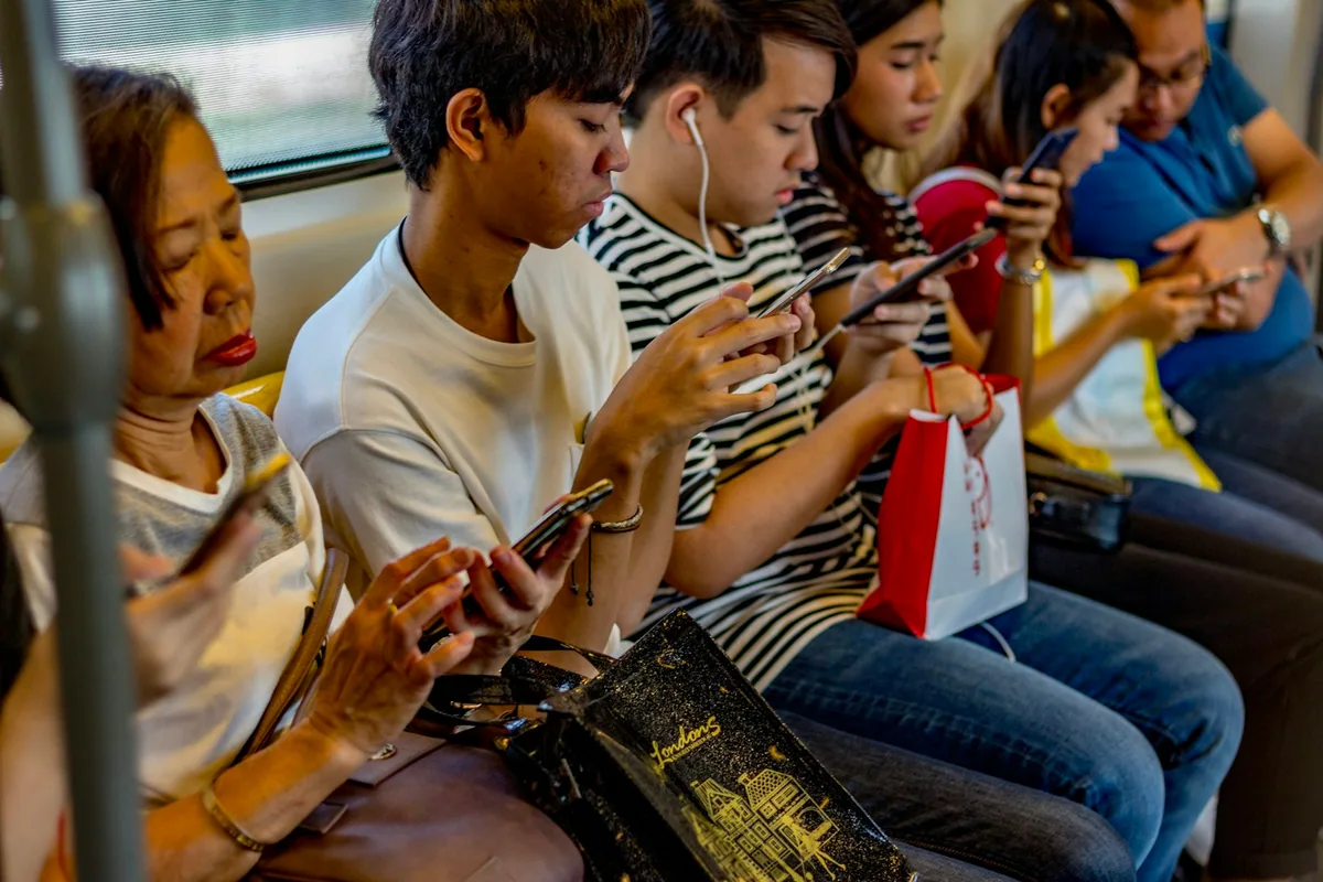 Passengers using different smartphones on a train.