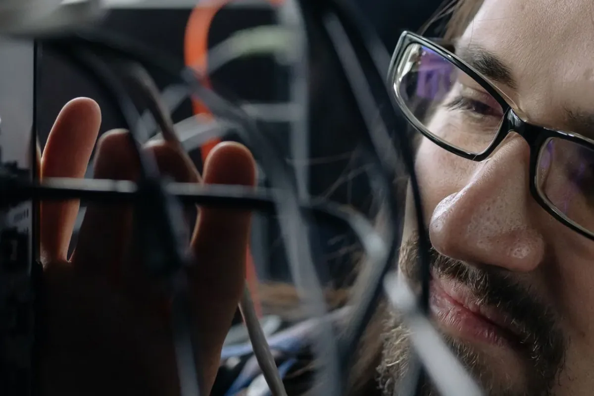 A technician inspects computer cabling.