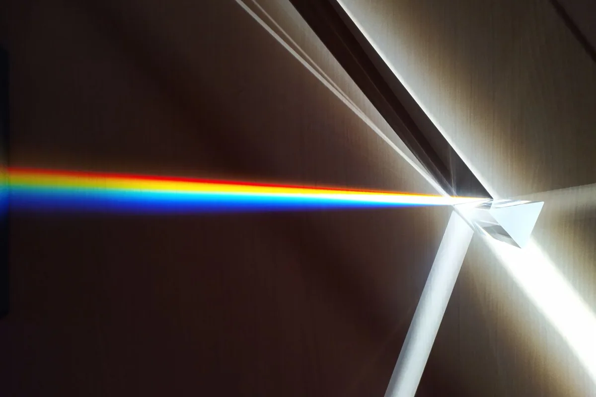 Licht wird durch ein Glasprisma in seine Spektralfarben zerlegt.