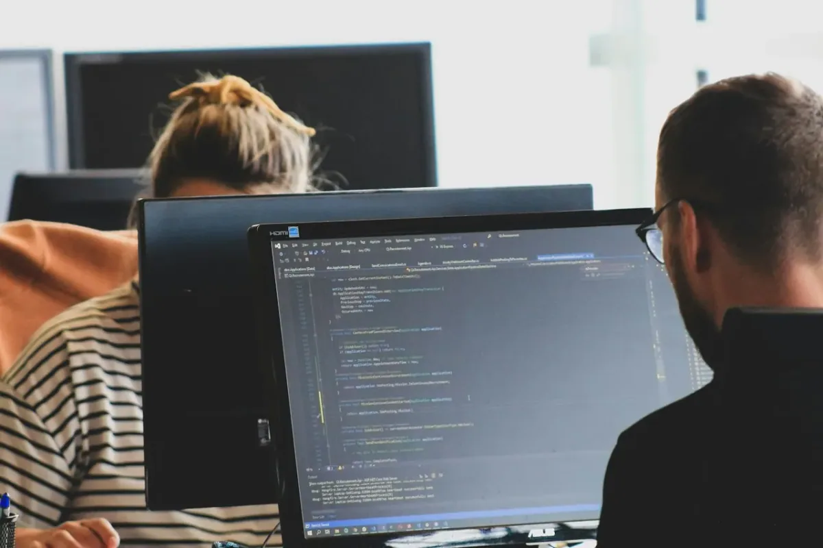 Entwickler arbeiten an Bildschirmen mit geöffnetem Programmcode.