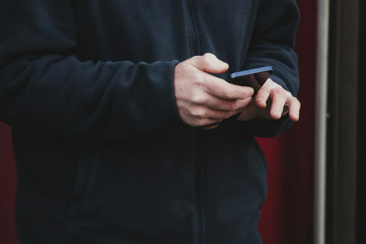 Nahaufnahme von Händen beim Bedienen eines Smartphones.